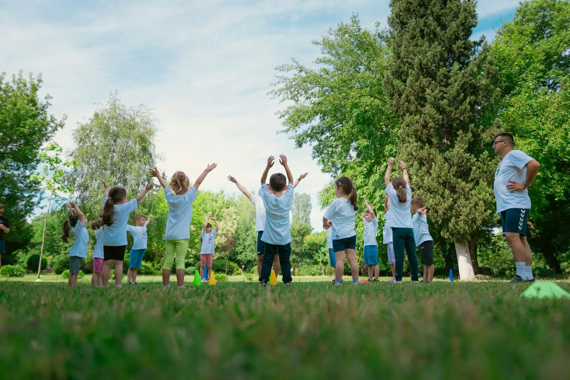 Eine Gruppe von Kitakindern steht im Kreis und wirft ihre Arme nach oben